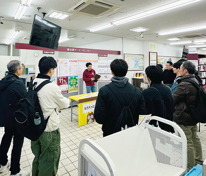 コープ学生総合共済のブースと学生の説明に耳を傾ける新入生たち